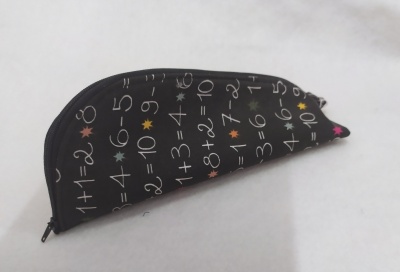 Estojo escolar preto com estampado de operações matemáticas e estrelas coloridas