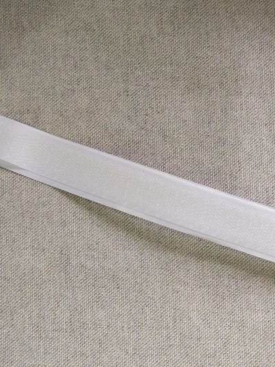 Fita branca lisa sobre superfície têxtil bege