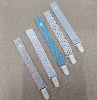 Pegs em tecido azul e cinza com padrões e clips brancos sobre fundo bege