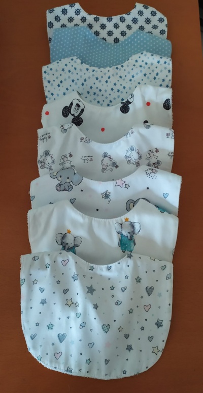 Seis babadores infantis coloridos com diferentes padrões de animais e estrelas