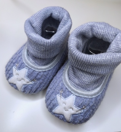 Sapatilhas de bebé cinzentas com estrela branca bordada na frente.