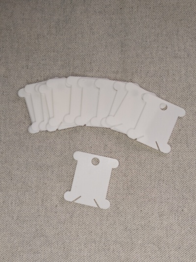 Cartões de papel branco com furos e entalhes sobre tecido cinza