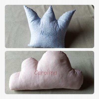 Duas almofadas, uma azul forma coroa com estrela e nome Miguel, outra rosa forma nuvem com nome Carolina
