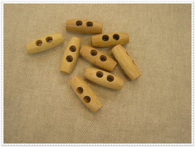 Botões de madeira clara com dois furos sobre tecido bege