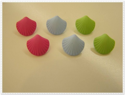 Seis objetos em forma de concha coloridos sobre mesa bege