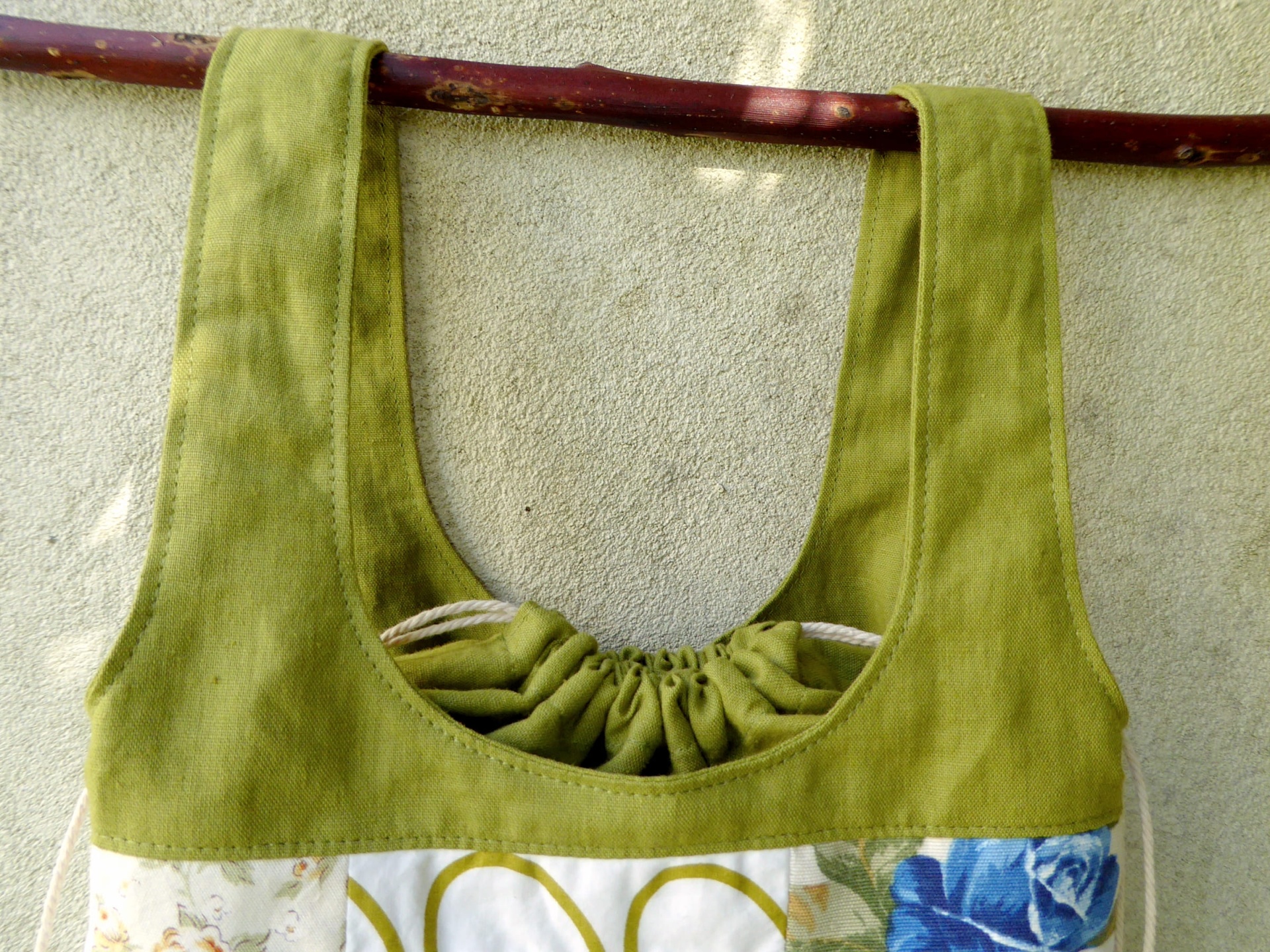 Sacos Com Asas / Saco do Pão Mala verde de tecido com alças largas pendurada numa vara de madeira
