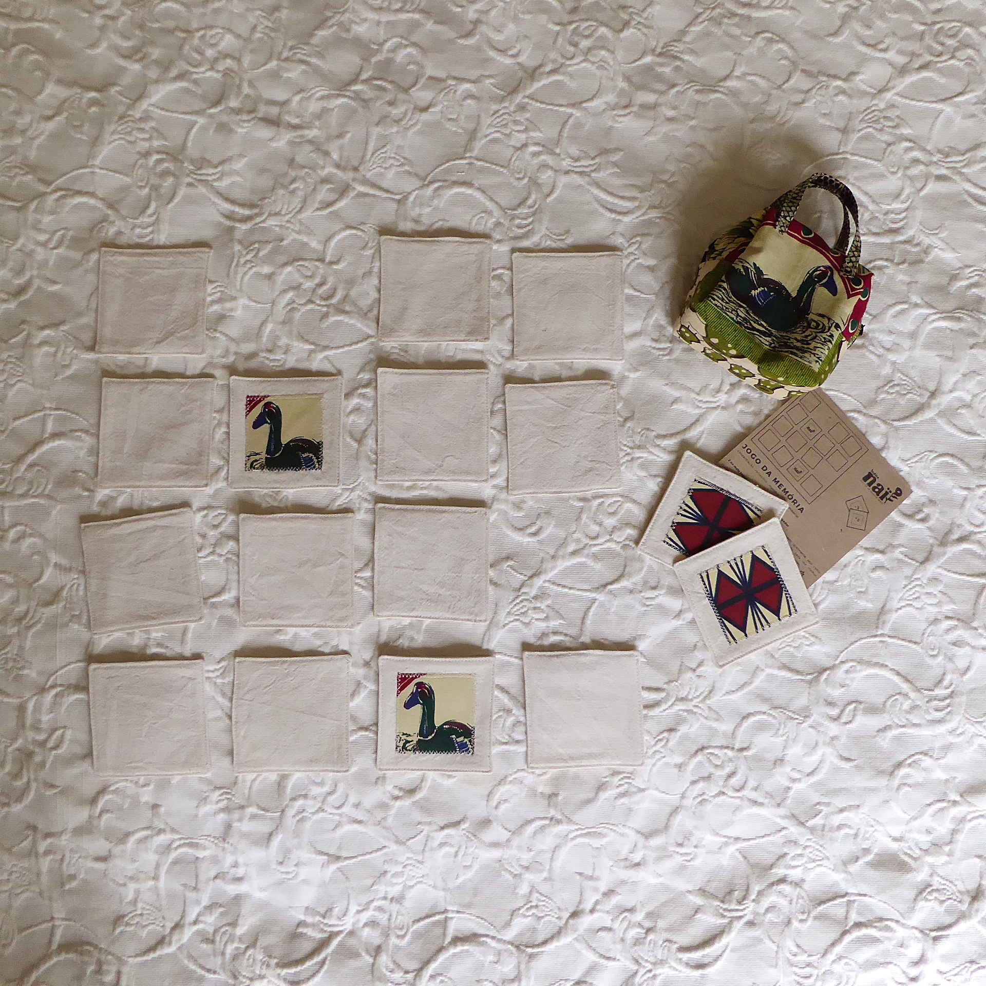 Jogos da Memória (suave - têxtil) Jogo da memória com cartas em tecido e saco colorido sobre superfície branca texturizada