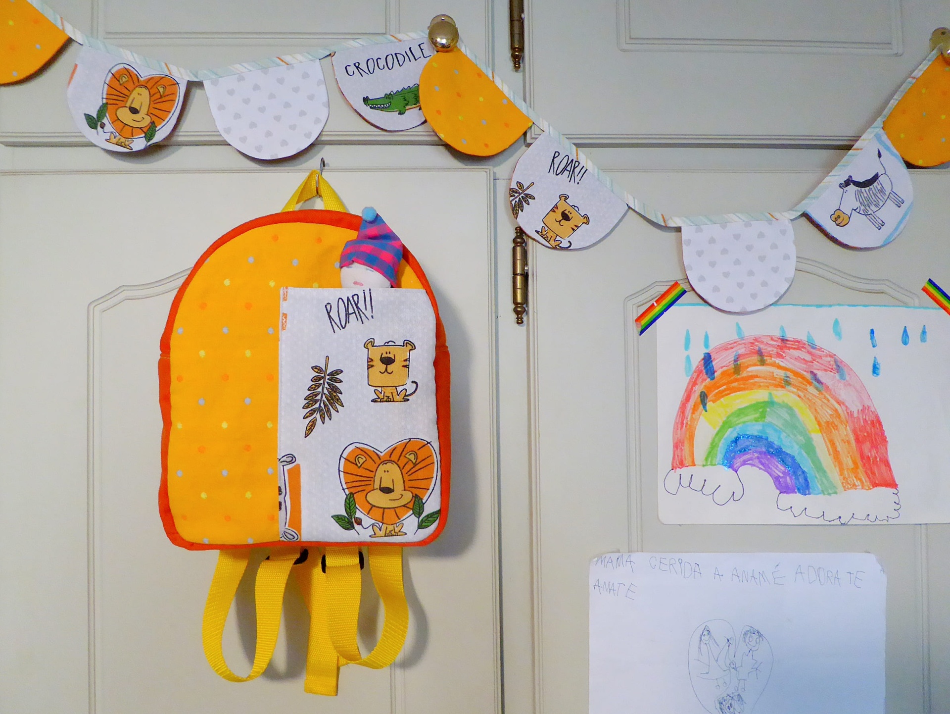 Mochila Pequena Mochila infantil amarela e laranja com padrões de animais e faixa decorativa pendurada