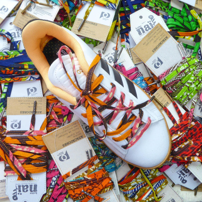 Cordões coloridos em tecidos diversos com sapato branco e etiquetas BOTICA NAIF