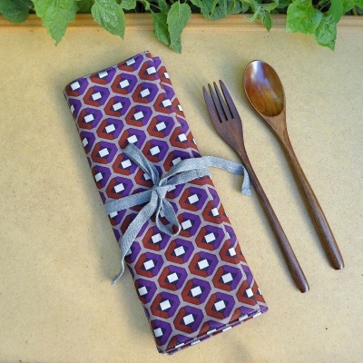 Utensílios de cozinha em madeira com estojo de tecido padrão geométrico roxo e vermelho.