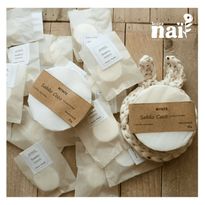 Sabão coco feito à mão com embalagem de papel e etiquetas de papel castanho sobre fundo de madeira, com logótipo botica naif