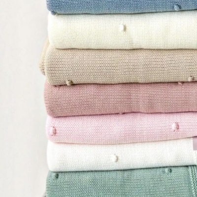 Empilhado de camisolas de malha em várias cores com pequenos pontos em relevo