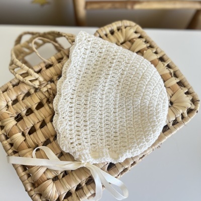Gorro branco de croché sobre mala de palha entrelaçada