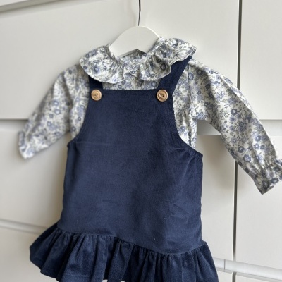 Vestido azul escuro de veludo com camisa floral branca e azul pendurados em cabide branco