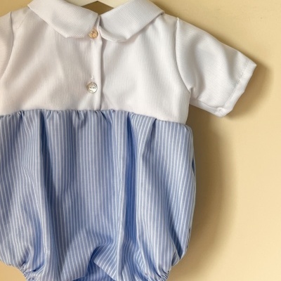 Macacão de bebé branco e azul às riscas pendurado num cabide