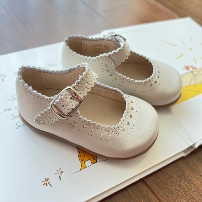 Sapatos infantis brancos com fivela metálica sobre livro ilustrado