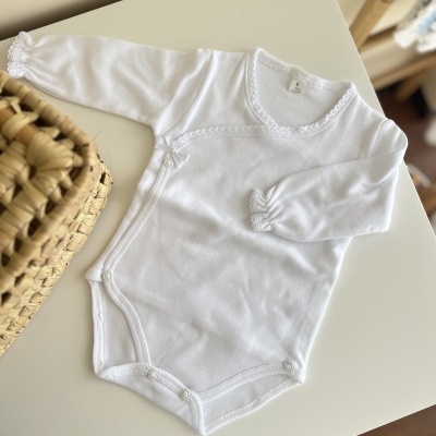 Body branco de manga comprida para bebé sobre mesa branca