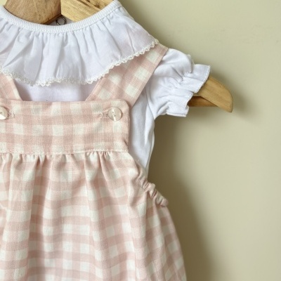 Conjunto infantil rosa e branco com camisa branca em cabide de madeira