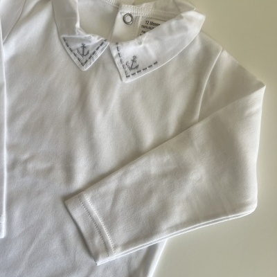 Camisola branca de manga comprida para criança com gola decorada com âncoras bordadas.