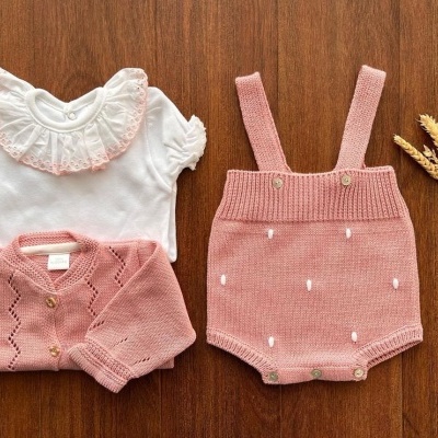 Conjunto de roupa de bebé com body branco, calções rosa com alças, cardigan rosa, espigas decorativas
