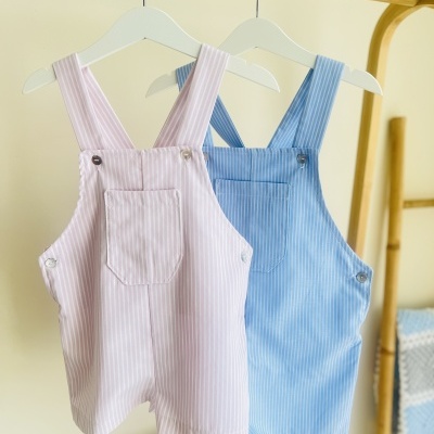 Macacões de bebé rosa claro e azul claro com riscas verticais em cabides brancos