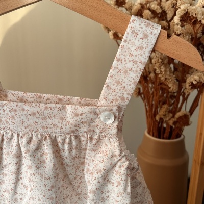 Detalhe de vestido ou saia com padrão floral bege em tecido branco suspenso em cabide de madeira
