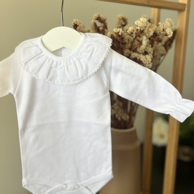 Body branco de criança com gola folhada pendurado em cabide branco