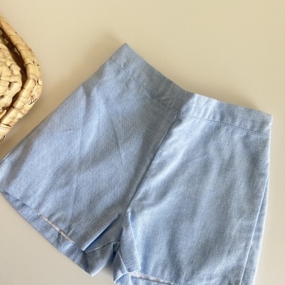 Calções femininos azul claro sobre superfície clara com objecto trançado ao lado