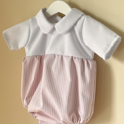 Romper de bebé branco e rosa com riscas e gola, pendurado numa cabide branca.