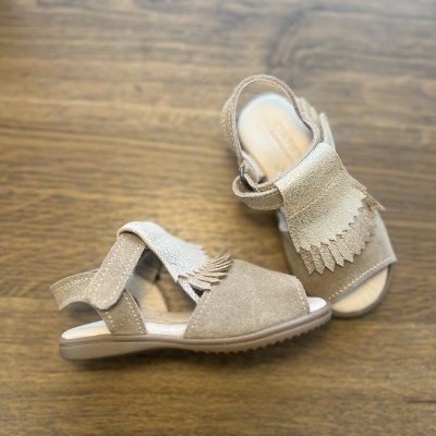 Sandálias infantis bege claro em camurça com velcro e franjas sobre madeira