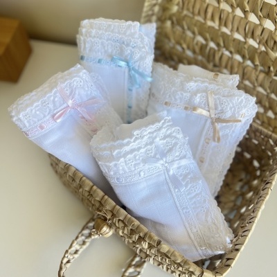 Lenços brancos com renda e laços em cesta de palha