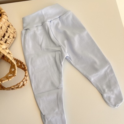 Calças azuis claras para bebé com pés fechados sobre superfície branca