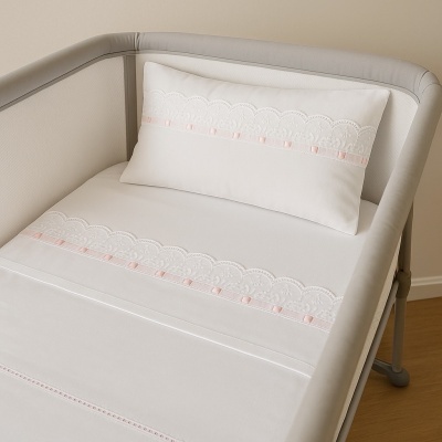 Cama de bebé com roupa de cama branca com renda e fita cor-de-rosa