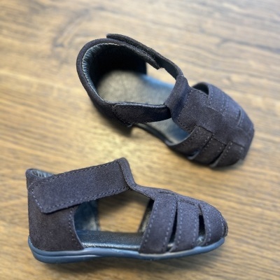 Sandálias infantis pretas de camurça com fecho de velcro sobre mesa de madeira