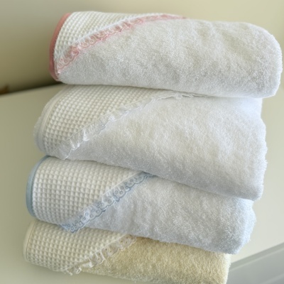 Toalhas de banho brancas empilhadas com bordas coloridas e texturas variadas.