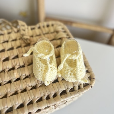 Sapatinhos de bebé amarelos de malha sobre cesta trançada