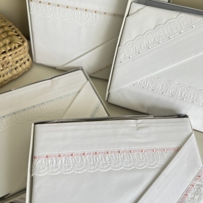 Conjunto de lençóis brancos bordados e embalados em caixas.