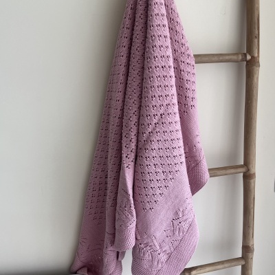 Manta rosa pendurada numa escada decorativa de madeira clara