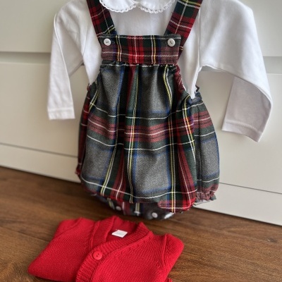 Roupa de bebé com body branco e vestido tartan, casaco vermelho dobrado
