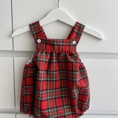 Macacão de bebé em tecido xadrez vermelho e verde pendurado em cabide branco