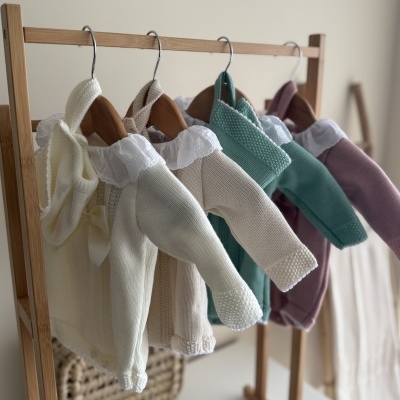 Camisolas de bebé em malha coloridas penduradas em cabides de madeira