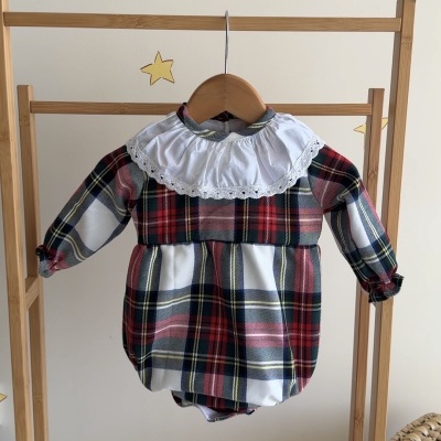 Body de bebé xadrez com gola branca e renda pendurado em suporte de bambu