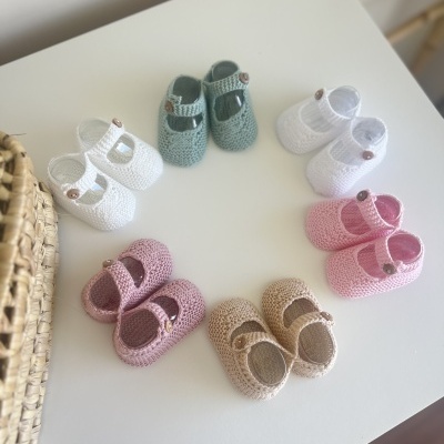 Seis pares de sapatinhos de bebé em crochet de várias cores sobre superfície branca