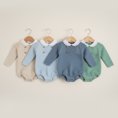 Quatro bodies de bebé de malha coloridos pendurados em cabides de madeira