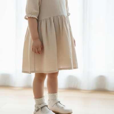 Vestido bege claro para criança com mangas curtas, meias brancas de renda e sapatos brancos com fivela