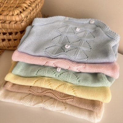 Roupas de malha para bebé em cores pastel empilhadas