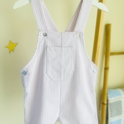 Jardineira riscada branca e rosa pendurada em cabide branco