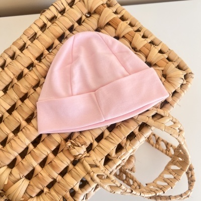 Gorro de bebé cor-de-rosa claro sobre mala trançada natural