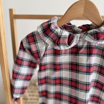 Vestido infantil tartan vermelho e branco com gola franzida pendurado em cabide de madeira