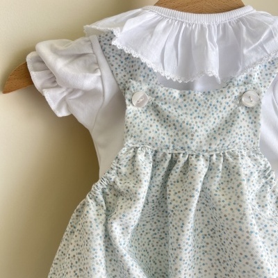 Roupinha de criança com vestido floral azul e camisa branca de mangas bufantes